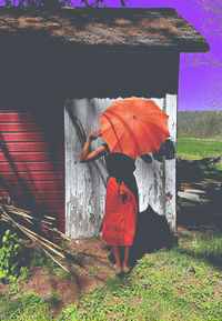 Rear view of woman with umbrella standing on field