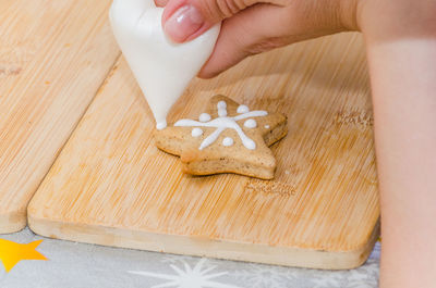 Cropped image of woman pouring cream on cookie