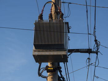 Low angle view of telephone pole against clear blue sky