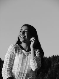 Low angle view of cheerful teenage girl against clear sky