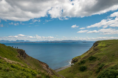 Unrecognizable people watching panorama of the sea from the lealt fall view point, skye, scotland
