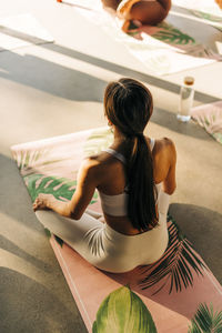 High angle view of woman exercising while sitting on exercise mat