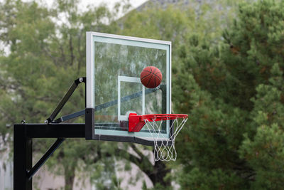 Basketball flying toward the backboard over the goal and net.