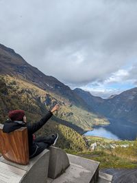 Rear view of woman sitting on rock against sky