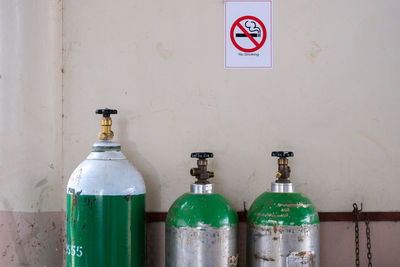 Old oxygen tanks arranged by the wall.