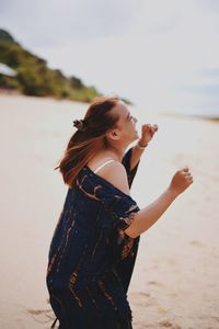 Side view of young woman standing on beach