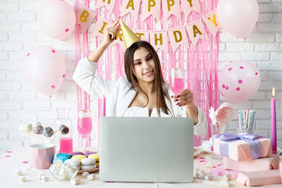 Brunette woman in white party clothes celebrating birthday using video call chatting with friends