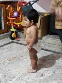 Rear view of shirtless boy playing with toy