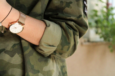 Close-up of human hand in front of clock