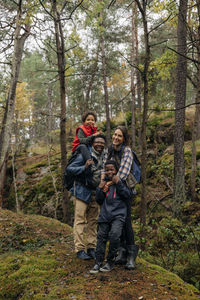 Happy family standing with each other in forest during vacation