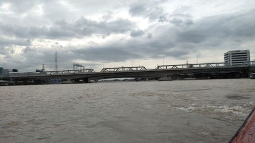 Bridge over river against cloudy sky