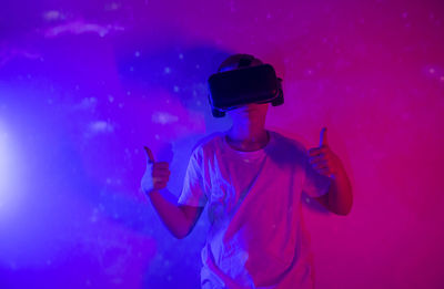 Rear view of man with arms raised standing against blue wall