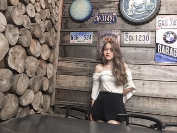 Portrait of smiling young woman standing against wall