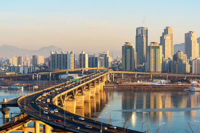 Bridge over river amidst buildings in city against sky