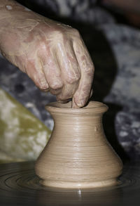 Midsection of man shaping earthenware pottery wheel 