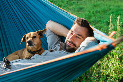 Portrait of attractive european man on hammock with cute sleepy dog.