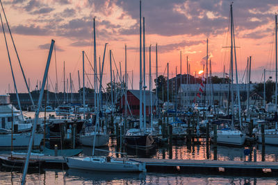 Sailboats moored at harbor against sky during sunset