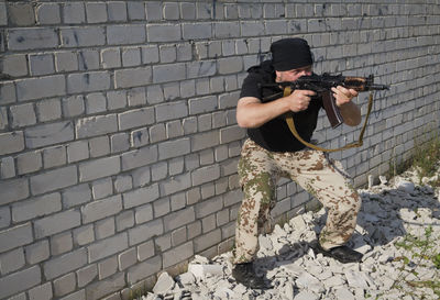 Full length of man standing against brick wall