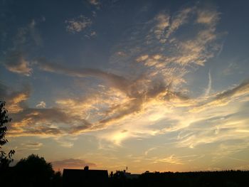 Low angle view of silhouette trees and buildings against sky during sunset