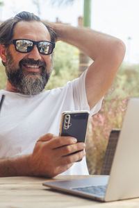 Young man using mobile phone while sitting on table