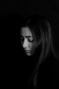 Close-up of sad young woman against black background