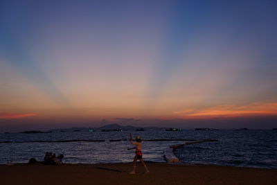 People standing on beach against sky during sunset