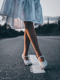 Low section of woman standing on road