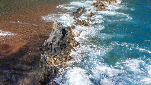 High angle view of waves splashing on rocks