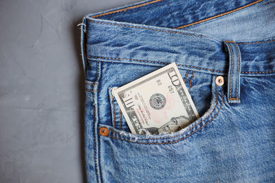 Directly above shot of paper currencies in jeans pocket on gray background