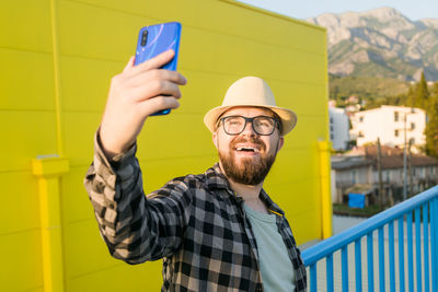 Happy man taking selfie through smart phone on sunny day