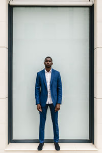Confident male african entrepreneur standing against window in city
