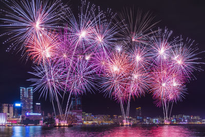 Firework display over river against sky at night