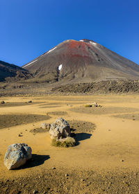 Scenic view of arid landscape against clear blue sky