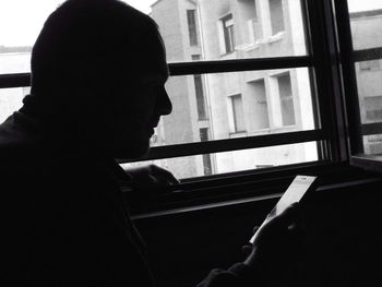 Portrait of man looking through window at home