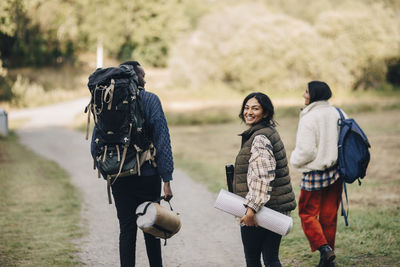 Portrait of smiling female with friends walking on footpath