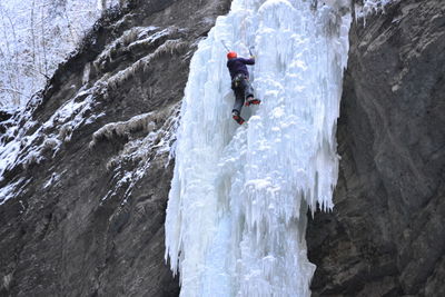 Low angle view of man climbing on glacier on mountain