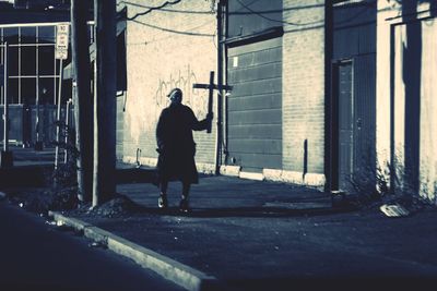 Rear view of man walking on street against buildings in city