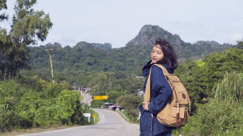 Young woman standing by trees on mountain against sky