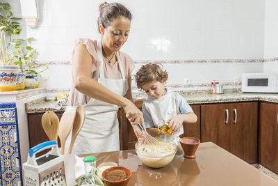 Mother and son preparing food in kitchen