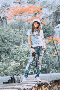 Portrait of smiling young woman standing against plants