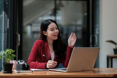 Young woman using phone while sitting on table