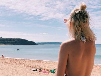 Rear view of woman at beach against sky