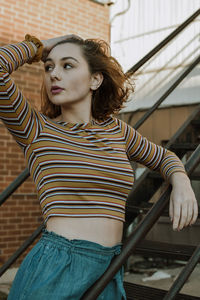 Portrait of beautiful young woman standing against railing