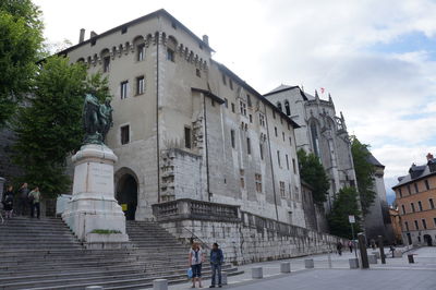 People standing by historic building at chambery against sky