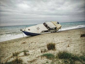 Abandoned boat on beach against sky