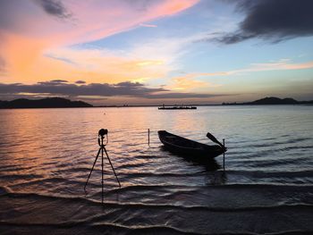 Silhouette boat moored on sea against sky during sunset