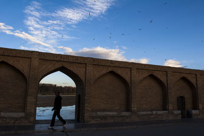 Man walking on bridge against sky