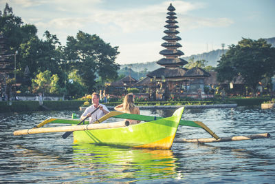 People on boat in lake against sky