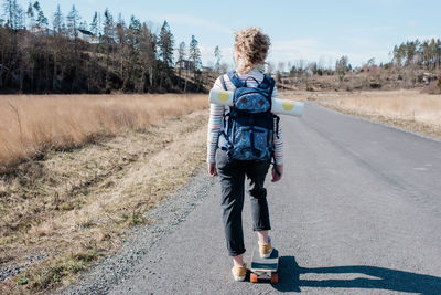 Woman carrying a yoga mat in a backpack whilst on a skateboard skating