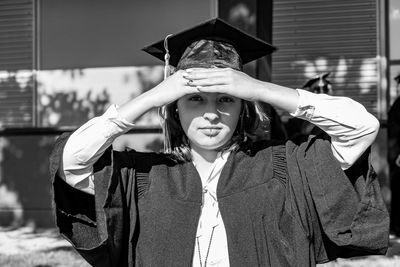 Portrait of young woman wearing graduation gown standing outdoors